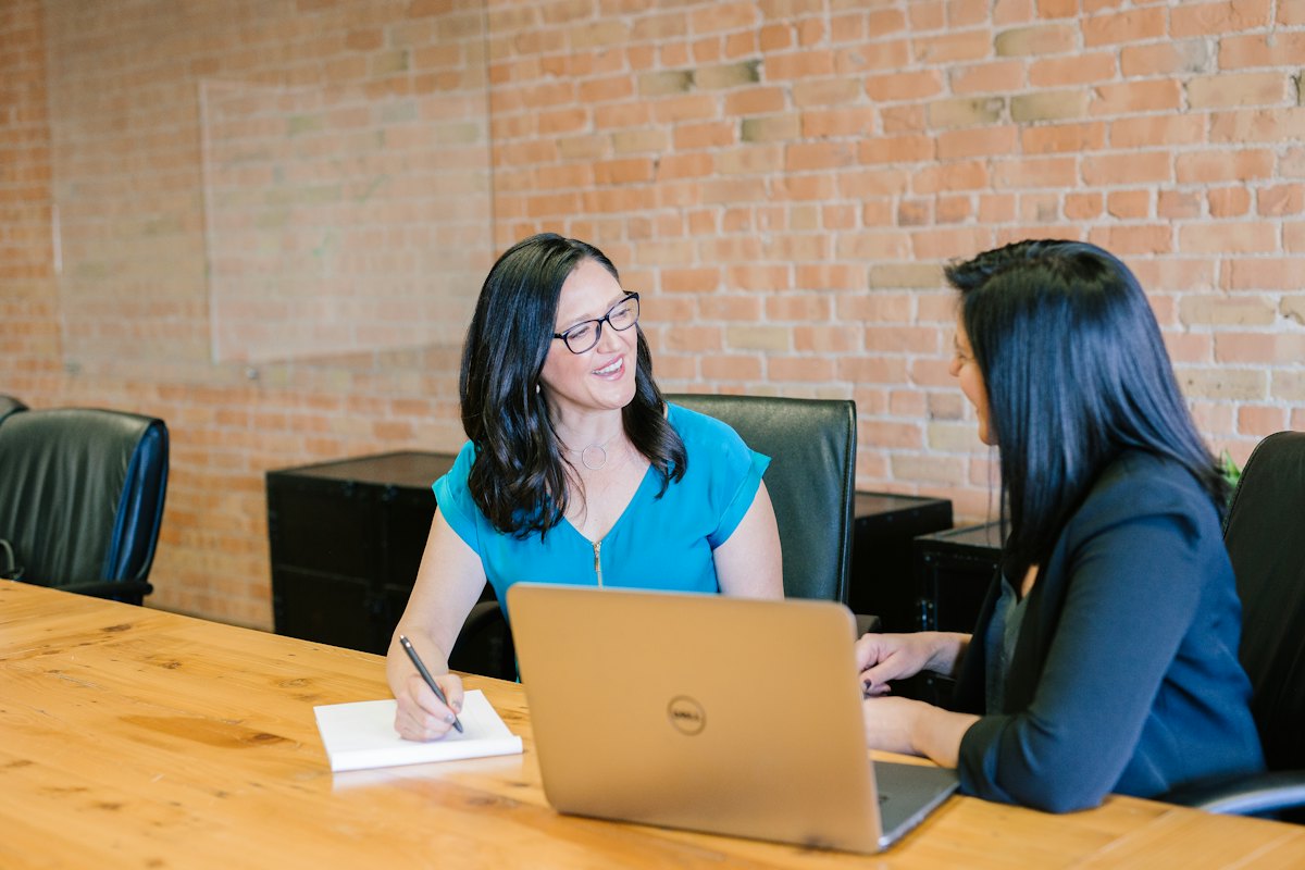 Dos mujeres en una entrevista de trabajo, sonriendo